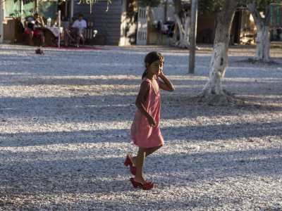 Una bimba ci viene incontro equilibrandosi su scarpe rosse da donna